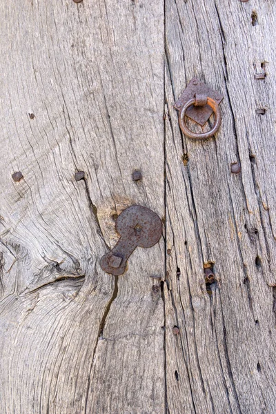 Ancient wood with ring, nails and mounting made of metal. Detail of an ancient door