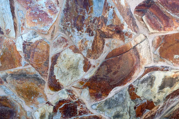 Detail of a wall cladding made of big smoothed natural stones in brown and gray