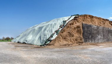 Big pile of silage covered with bright foil for a biogas plant  clipart
