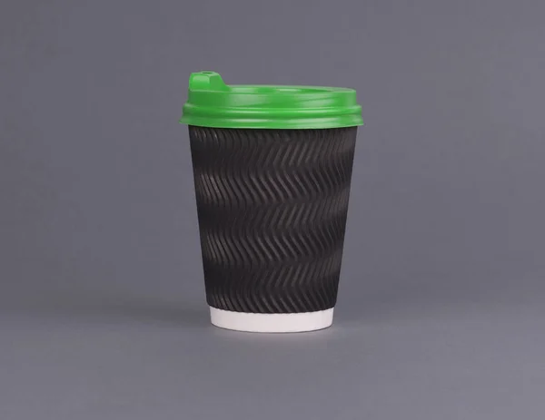 Tasse à café en papier noir avec un couvercle vert. Sur fond gris. Une tasse de café pour se maquiller — Photo