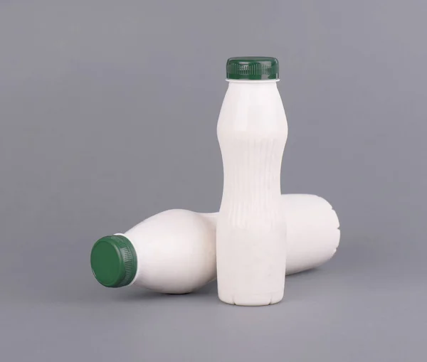 Біла пластикова пляшка з молоком, йогуртом або кефіром на сірому фоні. Зробити дизайн шаблону без мітки . — стокове фото
