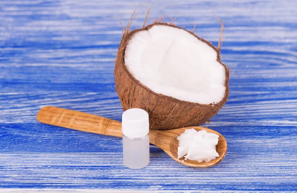 Noce di cocco con olio di cocco e latte su fondo di legno blu. Concetto di cibo sano — Foto Stock