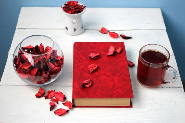 Bir kitap ve bir vazo Gül yaprakları çay