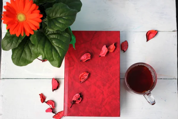 Bir fincan çay ve bir kitap beyaz bir tablo ile çiçek