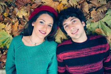 Genç çift düşen sonbahar yaprakları üzerinde döşeme