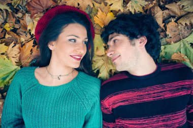 Genç çift düşen sonbahar yaprakları üzerinde döşeme