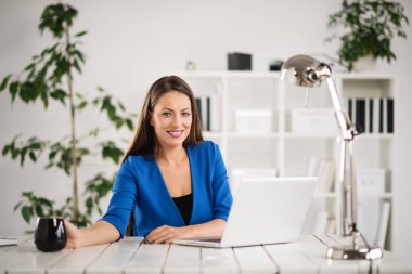 Kahve içen ve laptop kullanan genç bir kadın.