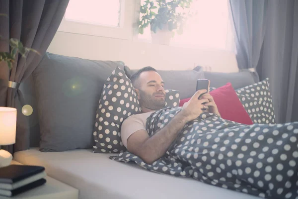 Hombre se despertó y usando el teléfono —  Fotos de Stock