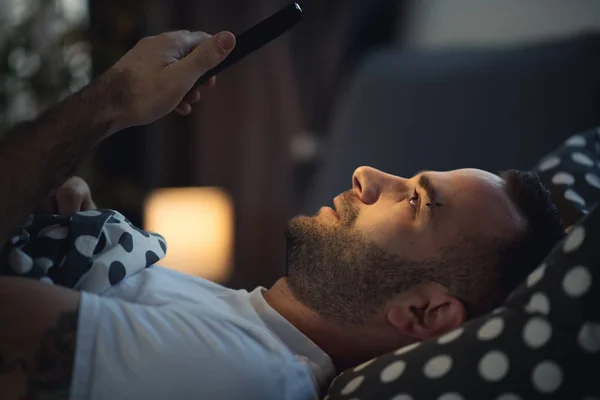 Young addict man awake in bed using smartphone — Stock Photo, Image