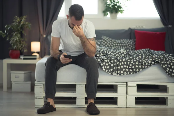 Jonge verslaafde man wakker in bed met smartphone — Stockfoto