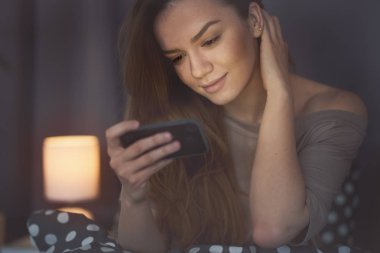 Evde akıllı telefon kullanan bir kadın. 