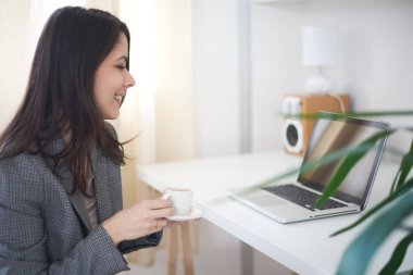 Evde dizüstü bilgisayarda çalışan bir kadın. 