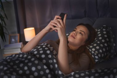 Evde akıllı telefon kullanan bir kadın.  