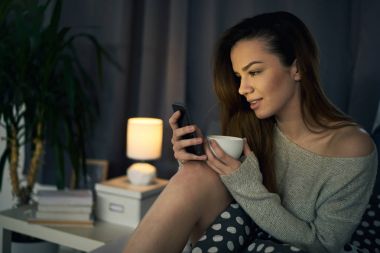 yatakta döşeme sırasında telefon kullanan genç güzel kadın 