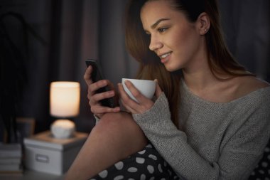 yatakta döşeme sırasında telefon kullanan genç güzel kadın