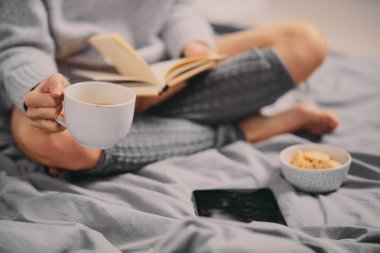 Kız sabah yatakta otururken kitap okuma