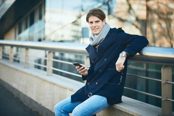 Joven hombre de negocios usando el teléfono inteligente mientras está de pie en la calle — Foto de Stock