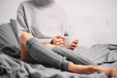 Sabahleyin yatakta otururken kahve içme kadın.