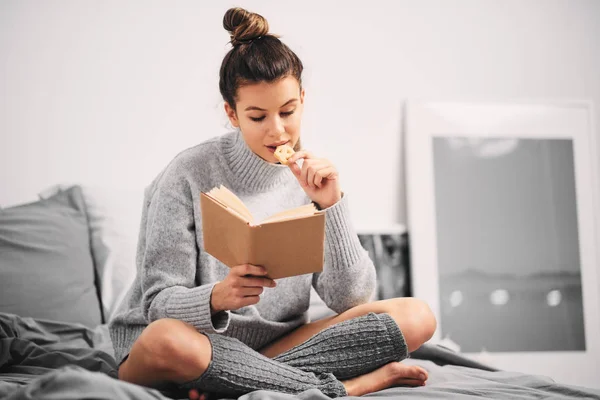 Frau Liest Buch Während Sie Morgens Auf Dem Bett Sitzt — Stockfoto