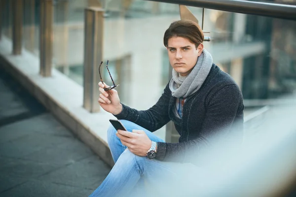 Ung Mand Sidder Udendørs Bruger Smart Telefon - Stock-foto