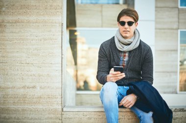 Açık ve kullanma akıllı telefon oturan genç adam.