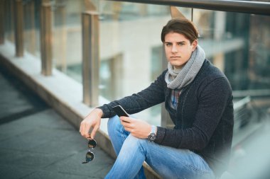 Açık ve kullanma akıllı telefon oturan genç adam.