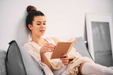 Kız sabah yatakta otururken kitap okuma