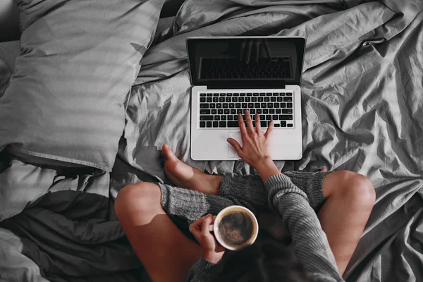 Vista aérea de la niña sentada en la cama y el uso de la computadora portátil, mientras que si — Foto de Stock