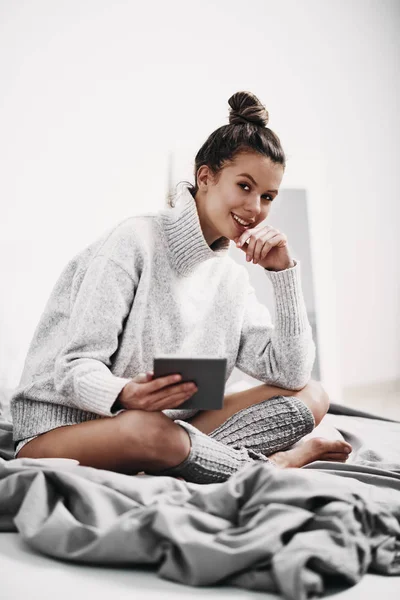 Mädchen, das morgens auf dem Bett sitzt und Tablet zum Lesen benutzt — Stockfoto