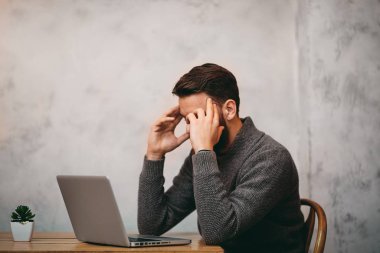 Kafede otururken baş ağrısı olan adam. Laptop önünde Merhaba