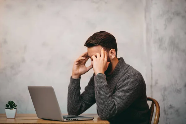 Un homme qui a mal à la tête alors qu'il était assis au café. Ordinateur portable devant salut — Photo