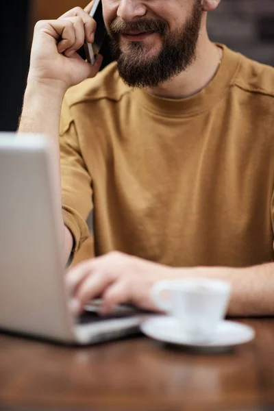 Człowiek za pomocą laptopa i inteligentny telefon, siedząc w kawiarni. Nowych technologii — Zdjęcie stockowe