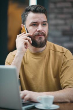 Kafede oturan ve akıllı telefon kullanan genç adam.