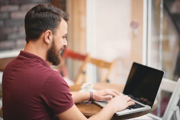 Homme assis dans un café et utilisant un ordinateur portable pour le travail . — Photo