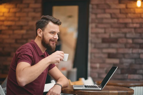 남자가 커피를 마시는 동안 식당에 앉아 노트북을 사용 하 여. — 스톡 사진