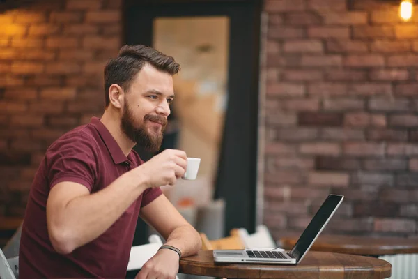 Man dricka kaffe och använder bärbar dator medan du sitter i cafeterian. — Stockfoto