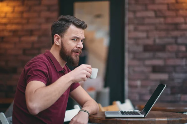 Man koffie drinken en het gebruik van laptop zittend in cafetaria. — Stockfoto