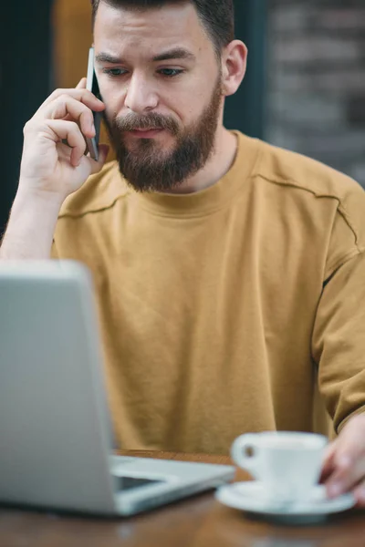 Homem usando laptop e telefone inteligente enquanto sentado no café. Nova tecnologia — Fotografia de Stock