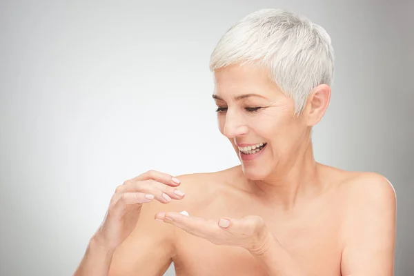 Head shot of beautiful senior woman putting on the cream. — Stock Photo, Image