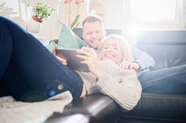 Çift evde kanepede uzanmış iken tablet kullanma. 