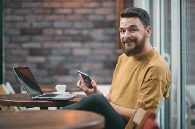 Kafeteryada oturan ve tablet bilgisayarı kullanan genç adam