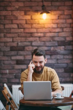 Kafede otururken dizüstü bilgisayar ve akıllı telefon kullanan adam. Yeni teknoloji