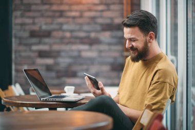 Kafeteryada oturan ve tablet bilgisayarı kullanan genç adam