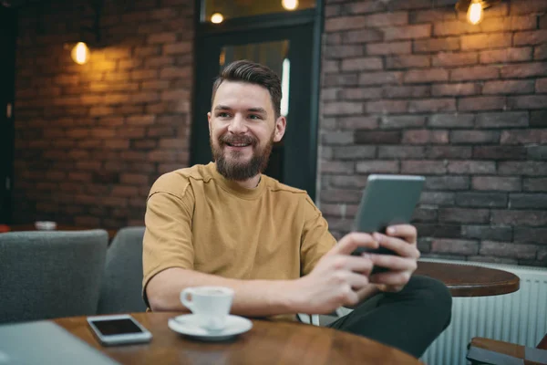 Ung man sitter i cafeterian och använder tablet PC — Stockfoto