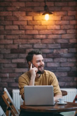Kafeteryada oturan ve akıllı telefon kullanan genç adam