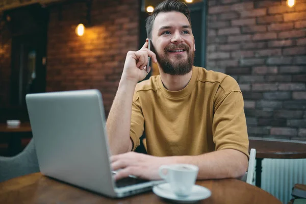 Ung man sitter i cafeterian och använder smart telefon — Stockfoto