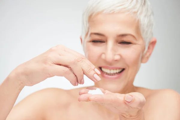 Close up of senior woman`s hands applying cream. — Stock Photo, Image