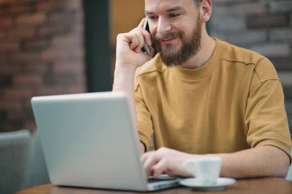 Kafede oturan ve akıllı telefon kullanan genç adam. — Stok fotoğraf