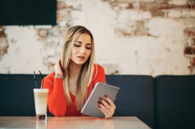 Kafe ve DRI otururken tablet kullanan genç beyaz kadın