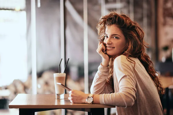 Jonge Kaukasische vrouw met behulp van Tablet PC zittend in café en dri — Stockfoto